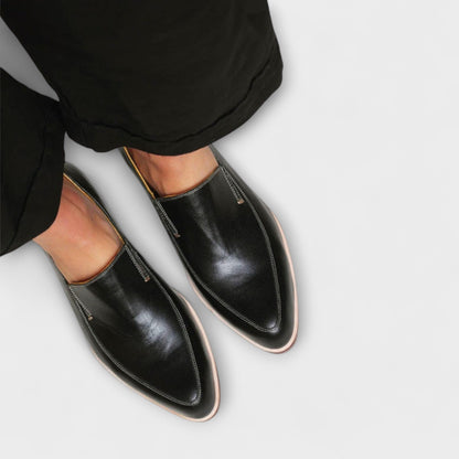 Black leather loafers with decorative topstitching and light brown trim sole, overhead view
