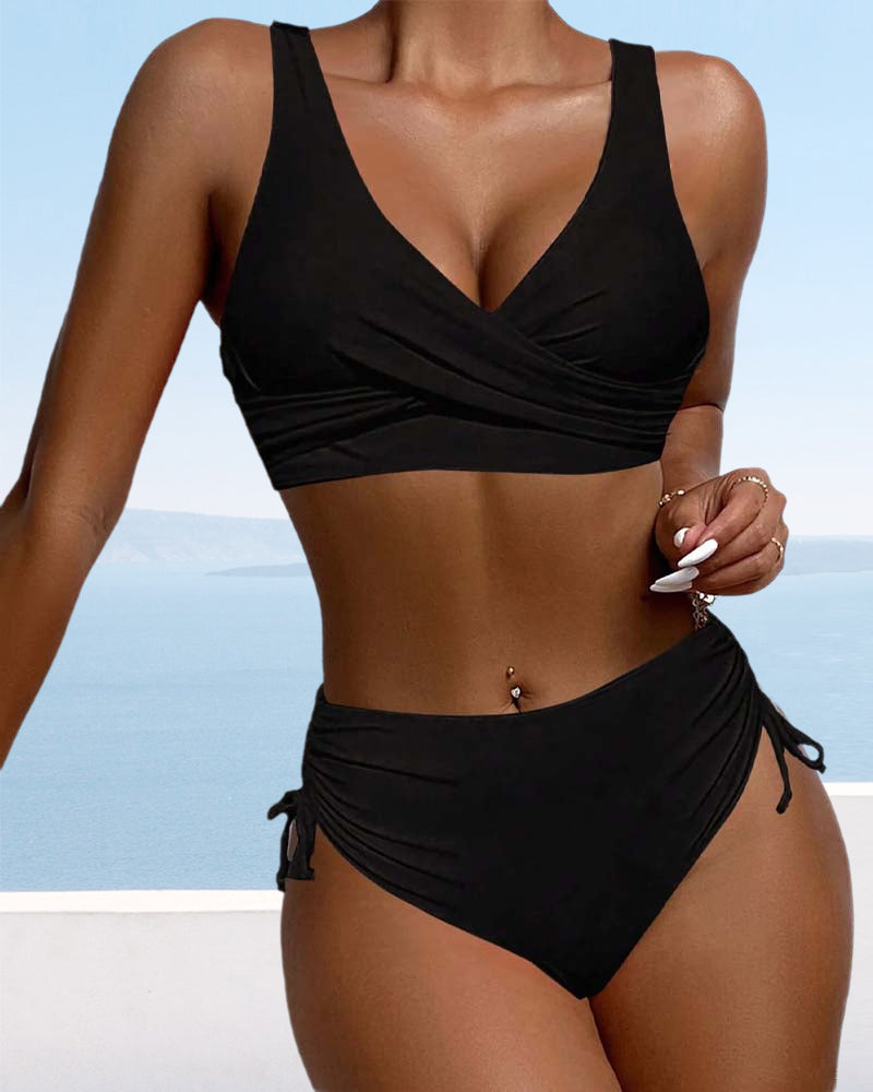 Black v-neck sleeveless bikini with side ties against ocean backdrop