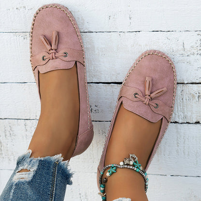 Mauve suede bow loafers with cushioned sole worn on feet, overhead view