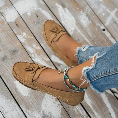 Tan suede loafers with bow detail and cushioned sole, worn with ripped jeans