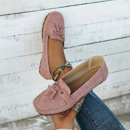 Mauve suede loafer with tassel bow and padded cushioned sole, held in hand
