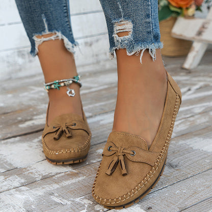 Tan suede bow loafers with visible stitching and cushioned rubber sole worn on feet