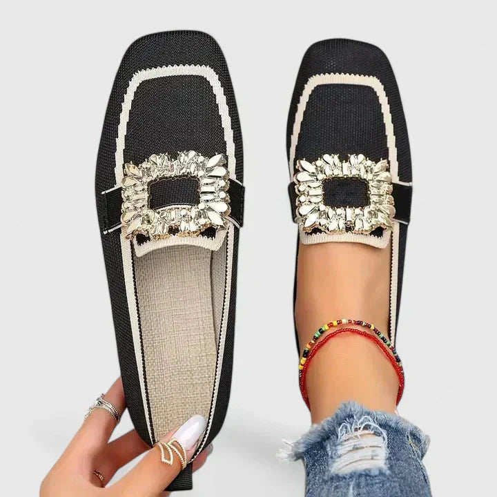 Black knit loafer with cream trim and gold decorative buckle, displayed flat and worn