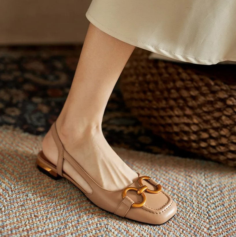 Beige loafer flat with decorative gold metal buckle and low heel in profile view
