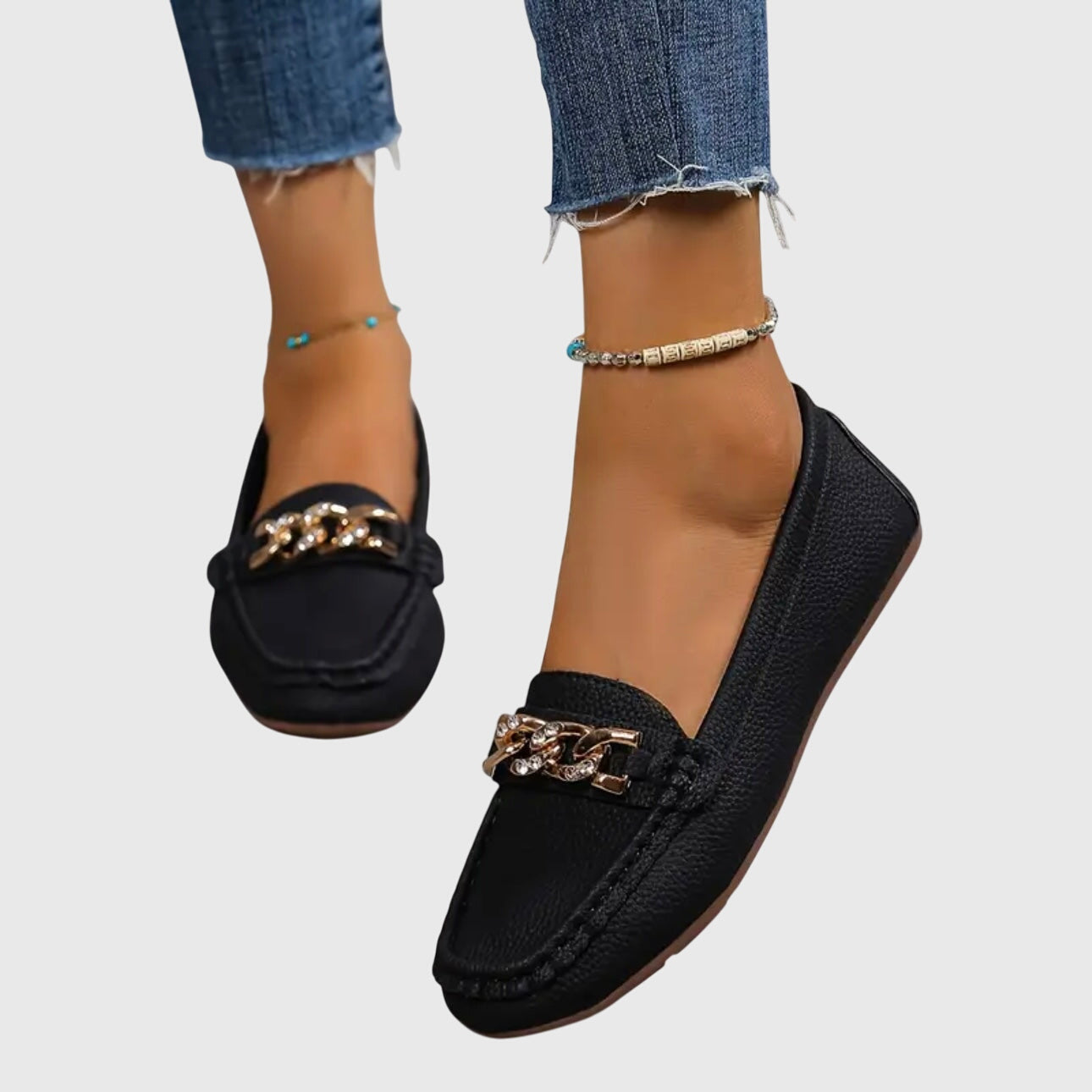 Black textured loafers with gold chain link embellishment worn on feet