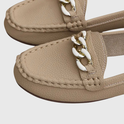 Close-up of beige loafer toe with white and gold chain link trim