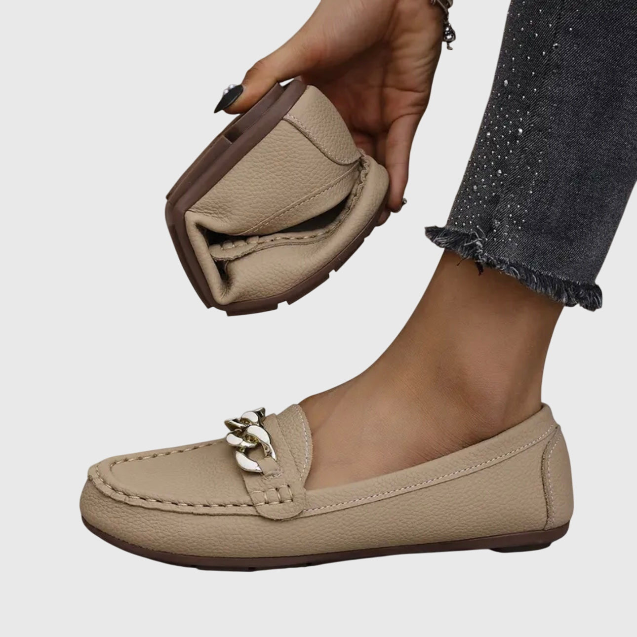 Beige chain link loafer held in hand showing textured leather