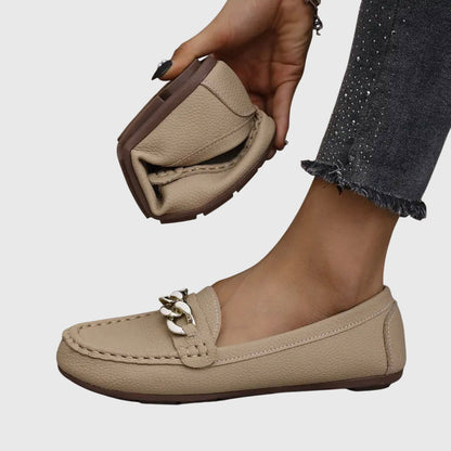Beige chain link loafer held in hand showing textured leather