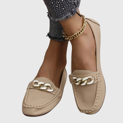 Beige loafers with white and gold chain link worn on feet