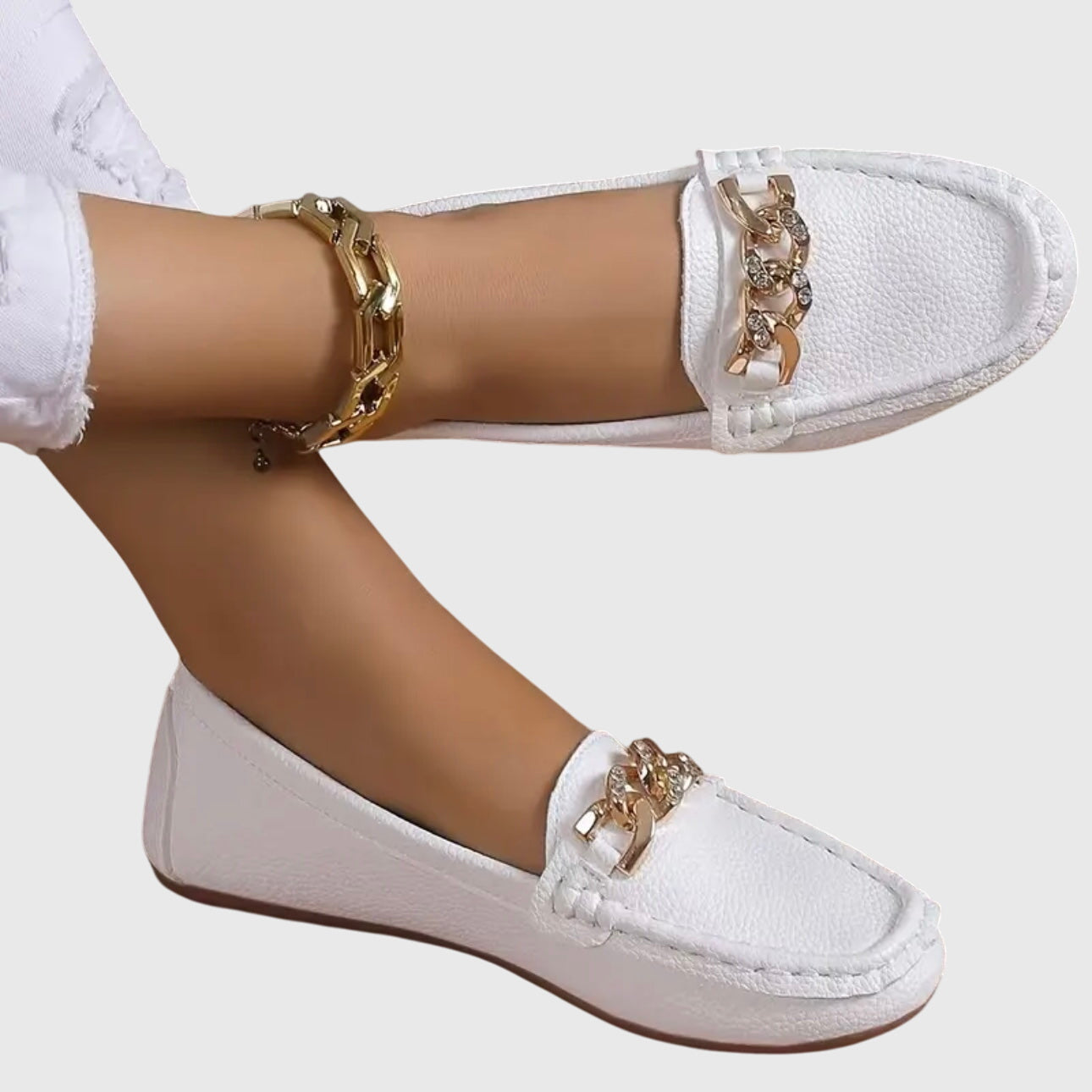 White leather chain link loafers with gold hardware on feet