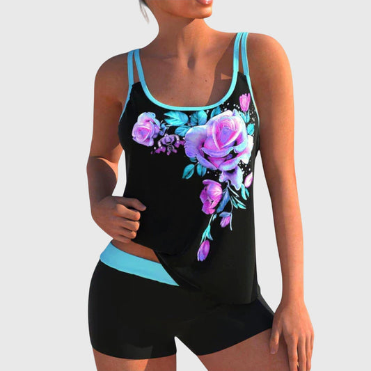 Black tankini top with purple and magenta floral print and turquoise trim paired with black shorts