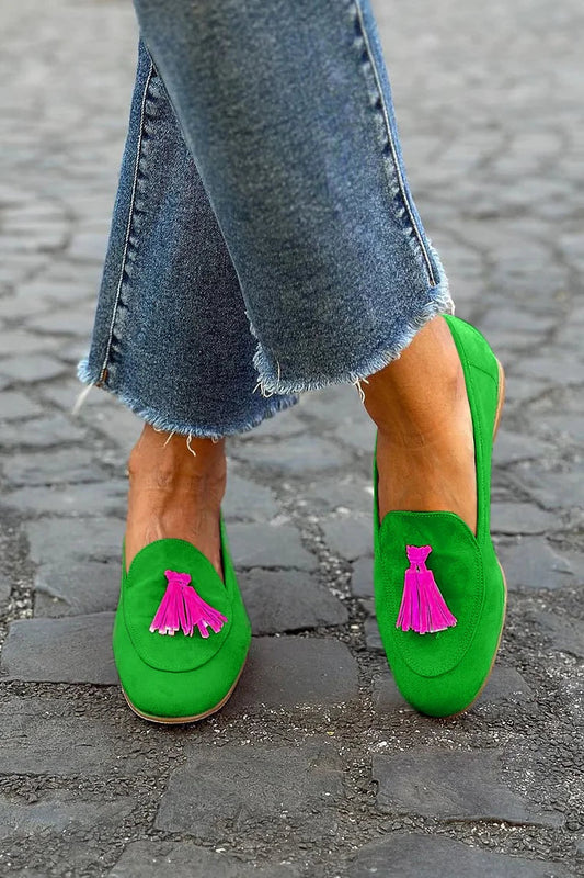 Bright green suede loafers with pink tassel accents on feet