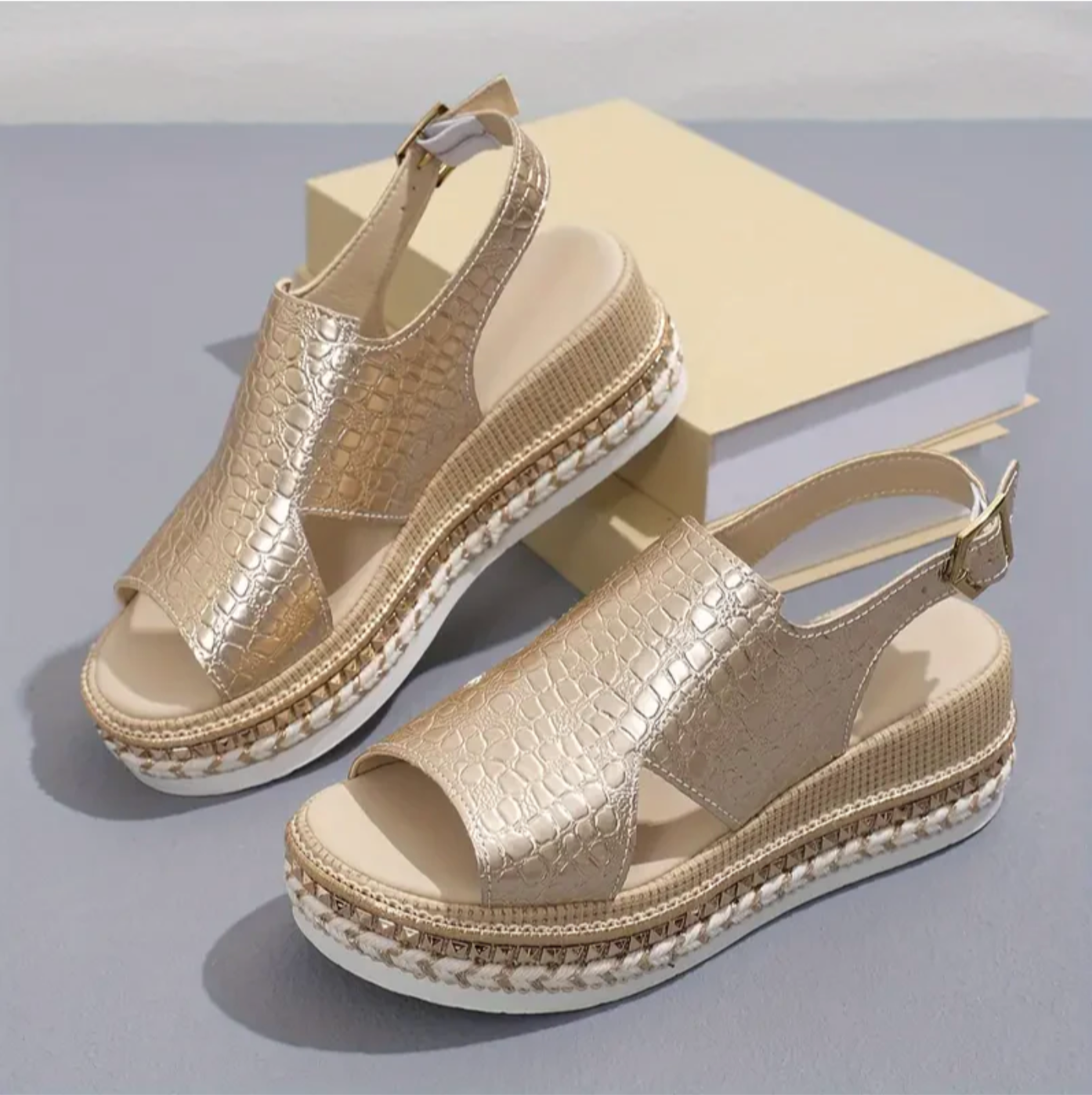 Studio shot of pair of gold platform sandals with croc pattern and white trim