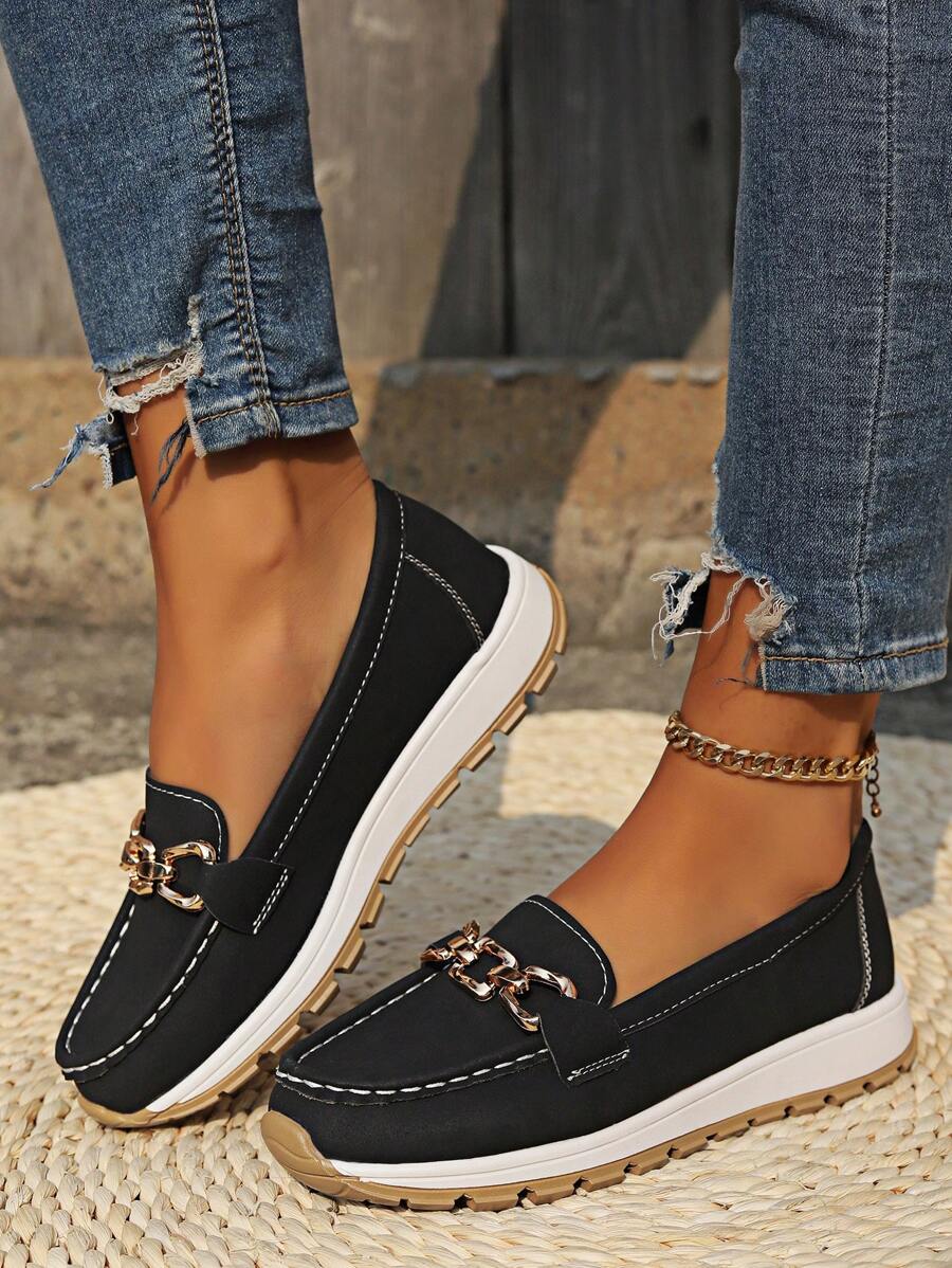 Black loafers with gold chain hardware and white sole, styled with distressed jeans