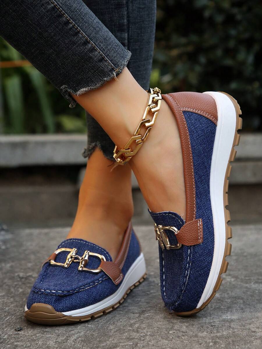 Navy and tan loafers with gold chain detail and white midsole, worn with ripped denim