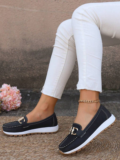Black loafer with contrasting white stitching and gold hardware accent