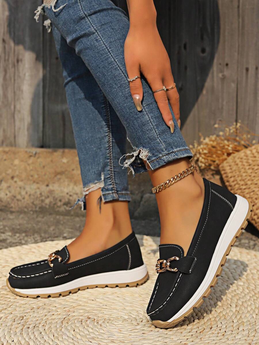 Black loafer with gold hardware worn with distressed blue jeans