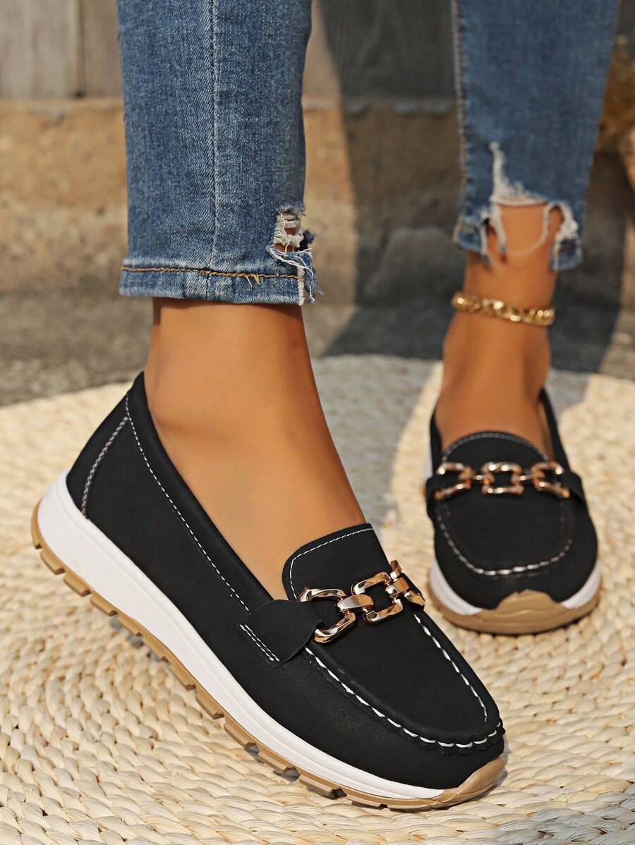 Black loafer with gold chain hardware and tan rubber sole detail