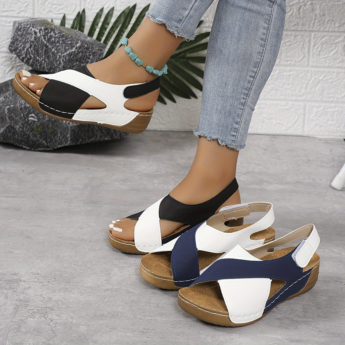 Black and white platform sandals with adjustable back strap, multiple pairs displayed on ground