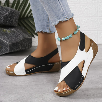White and black platform sandals with adjustable back strap, worn on feet from side angle