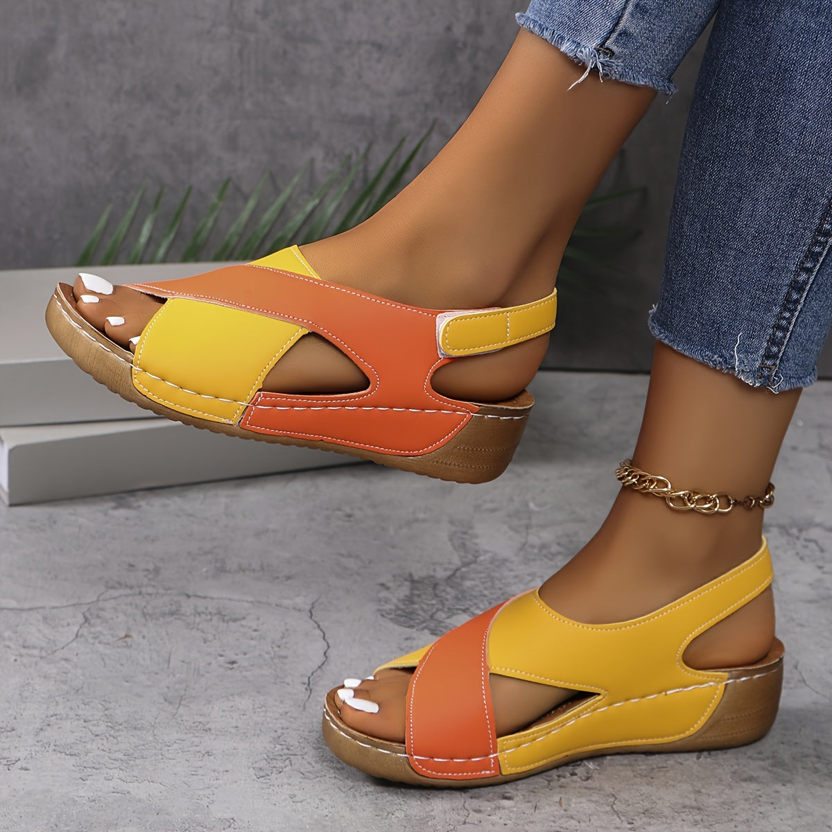 Yellow and orange platform sandals with adjustable back strap, worn on feet showing color-block design