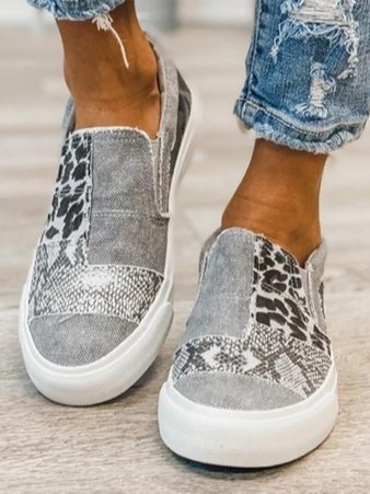 Women wearing gray and leopard print canvas slip-on sneakers with distressed denim