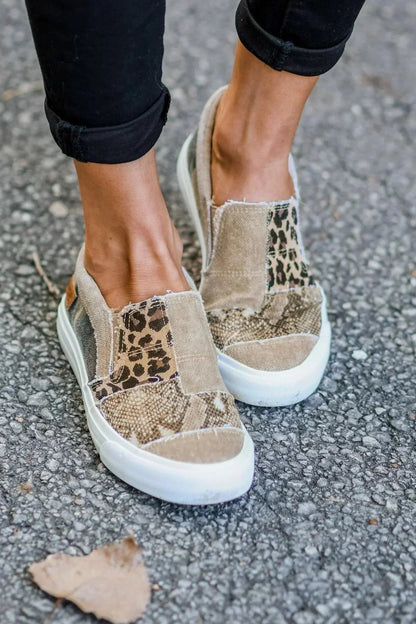 Women's leopard and snake print canvas slip-on sneakers with white sole, worn with black jeans