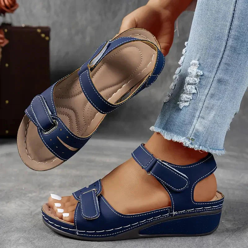 Navy blue adjustable strap wedge sandals displayed from side angle with cushioned footbed