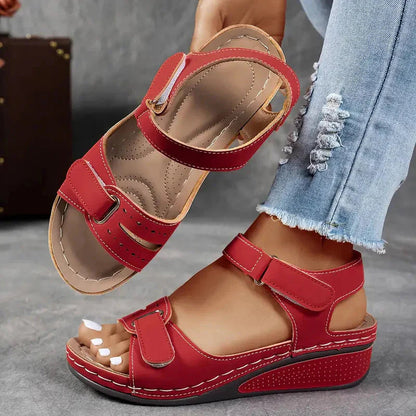 Red adjustable strap wedge sandals displayed from side with perforated footbed detail