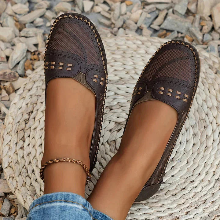 Top view of brown cushioned loafer flats showing perforated moc toe design and stud details