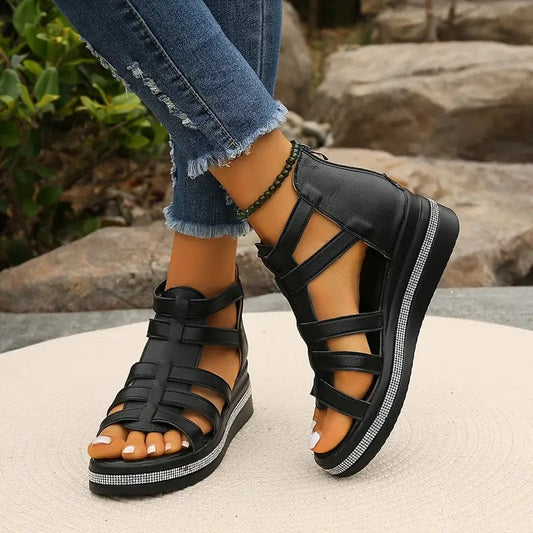 Black strappy platform sandals with rhinestone trim and thick sole, worn with distressed jeans