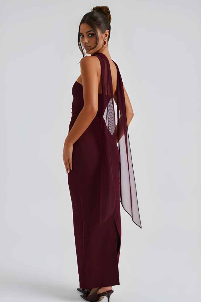Side back view of burgundy strapless dress with flowing sheer scarf overlay