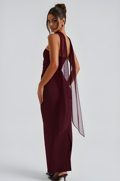 Side back view of burgundy strapless dress with flowing sheer scarf overlay