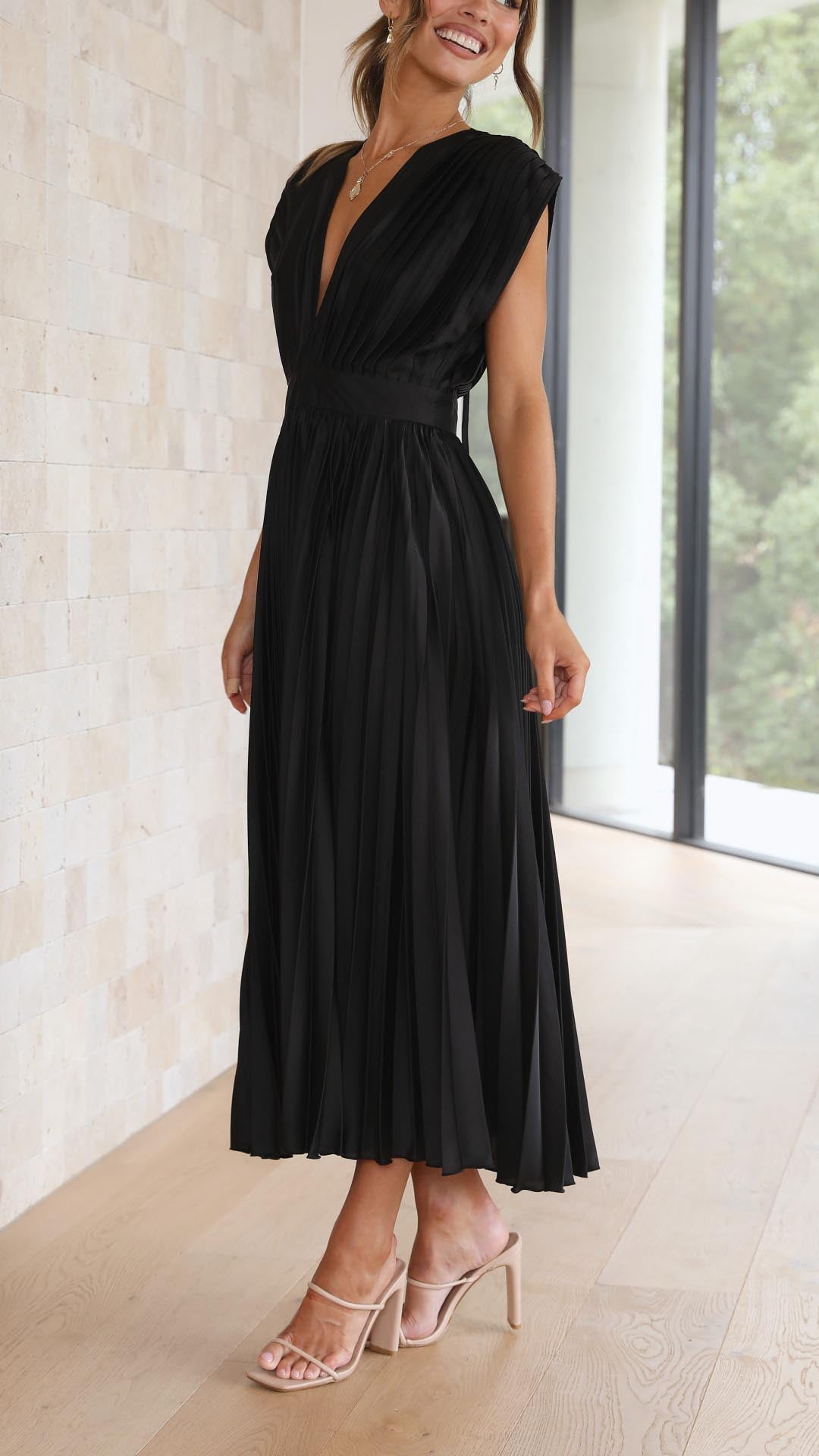 Side profile of black pleated midi dress showing high waist definition