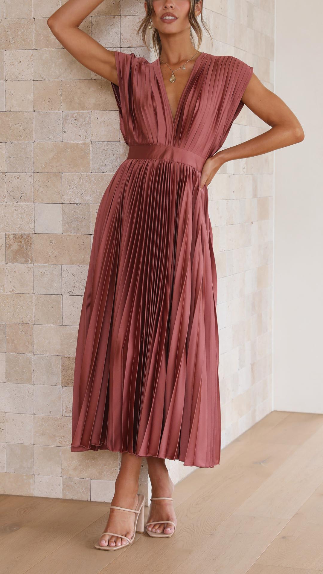 Side view of mauve pleated midi dress showing v-neckline and flowing skirt