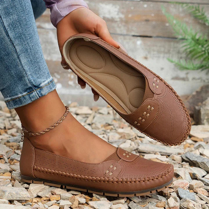 Brown loafer flat with arch support insole held up showing cushioned footbed and design details