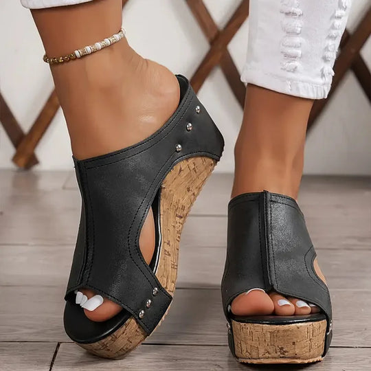 Side view of black studded wedge sandals showing cork platform and metal studs