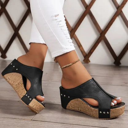 Black studded cork wedge mules with peep toe worn with white pants