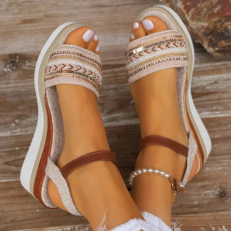 Flat lay of woven platform wedge sandals showing cream geometric patterns and brown leather accents