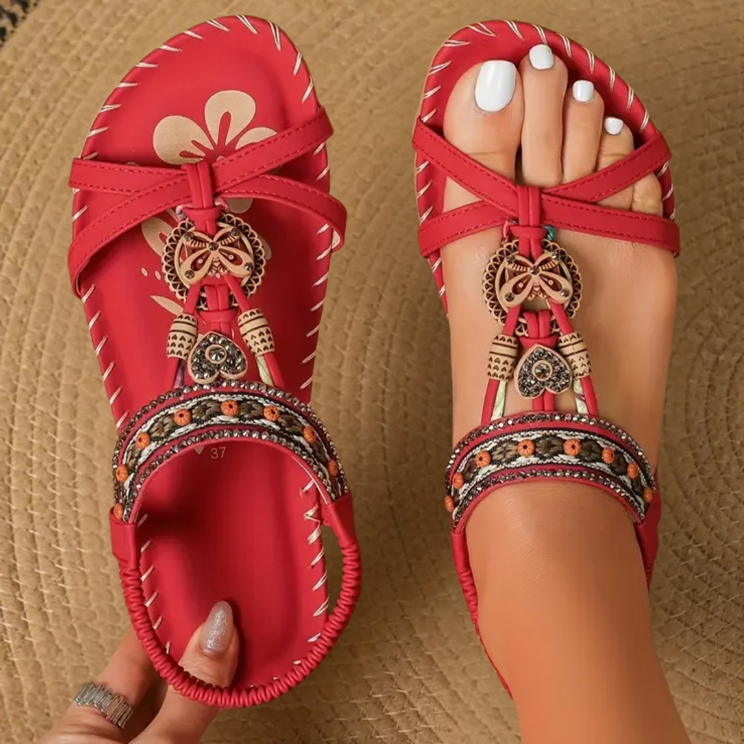 Red orthopedic sandal with cross straps and ornamental charm detail
