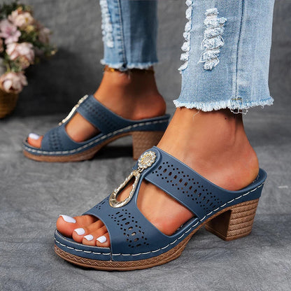 Navy blue perforated block heel sandal mule with white stitching and gold chain accent