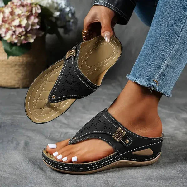 Black perforated thong orthopedic sandal with tan sole and metallic buckle detail